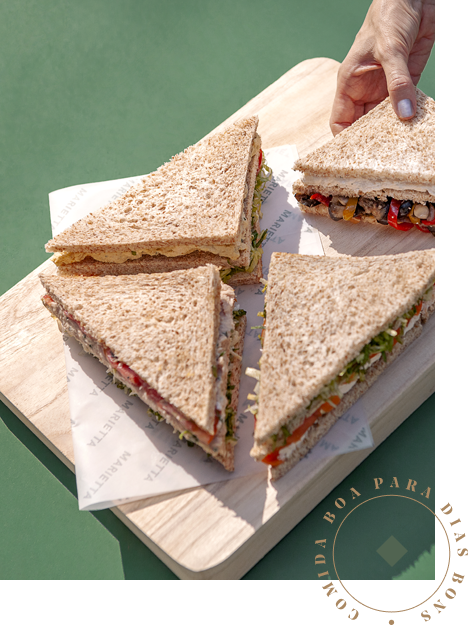 Quatro sanduíches sobre uma tábua e o texto “Comida boa para dias bons” no canto inferior direito.