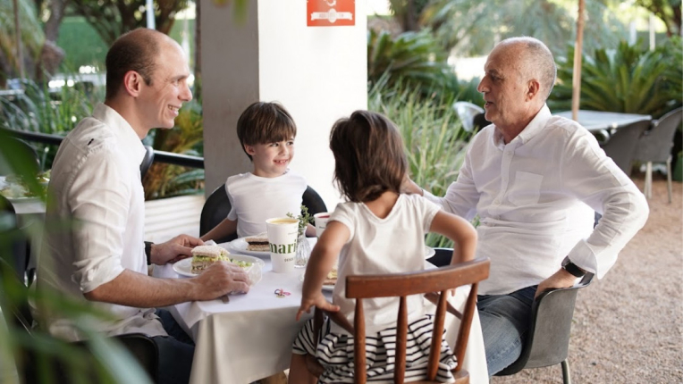 Dois adultos e duas crianças sentadas à mesa com produtos da Marietta.